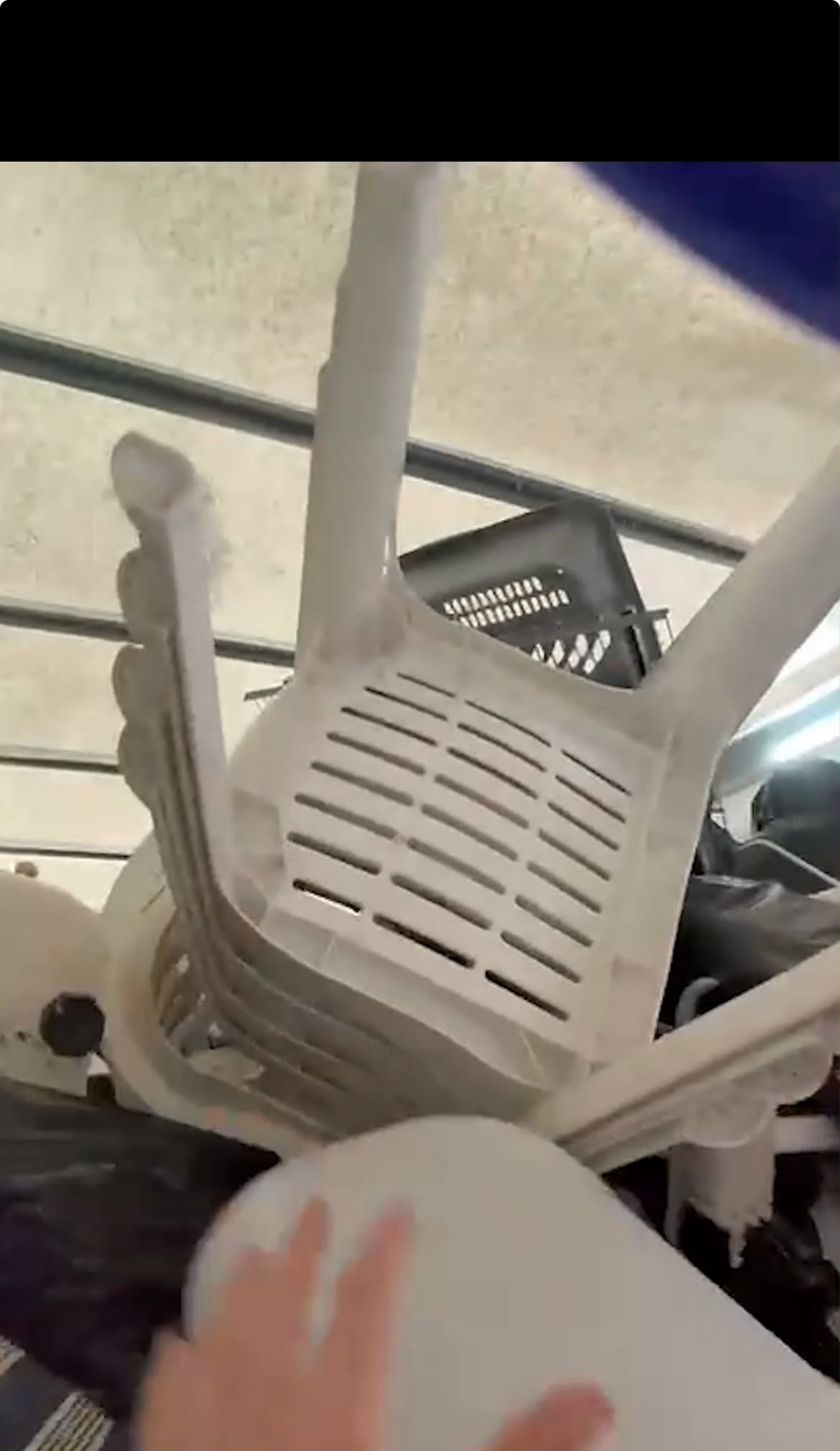 Stacked white plastic garden chairs and a black plastic crate held back in the van rather than tipped